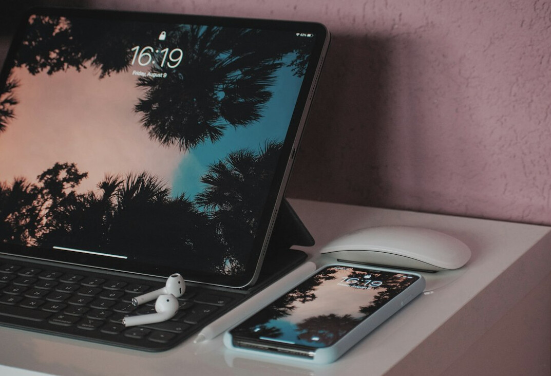 Laptop with charts next to a notebook on a wooden desk